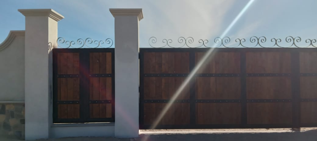 Muro y barda perimetral — Portón de madera con herrería de forja