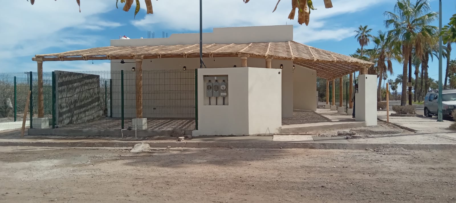 Restaurante TBC — Vista exterior: volumen blanco y pérgola de palo y carrizo